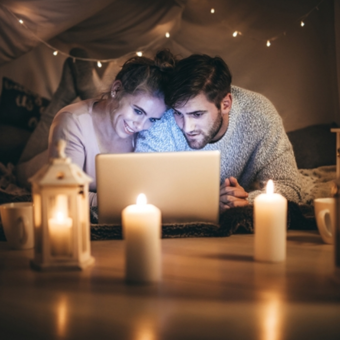 Tall-Couple lying on bed looking at a laptop